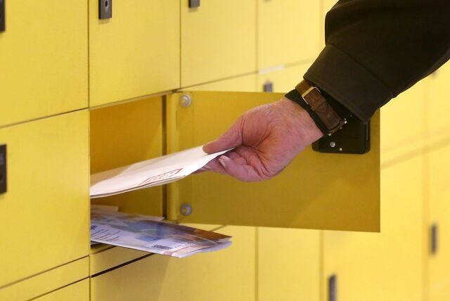 Eine Hand zieht Briefe aus einem Postfach.
