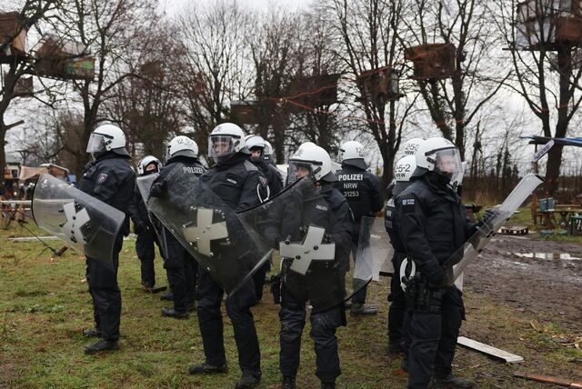 Polizisten stehen vor Baumhäusern von Klimaaktivisten im besetzten Braunkohleort Lützerath. Der Energiekonzern RWE will die unter Lützerath liegende Kohle abbaggern. Dafür soll der Weiler auf dem Gebiet der Stadt Erkelenz am Braunkohletagebau Garzweiler II abgerissen werden.