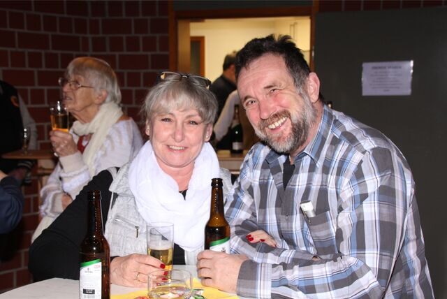 Eine Frau und ein Mann stehen mit zwei Flaschen Bier an einem Bistrotisch.