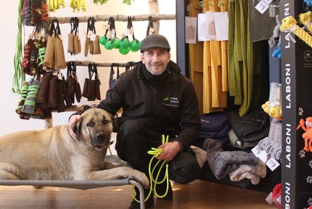 Dirk David Schmitt sitzt mit Kangal-Hündin Kaira vor Waren-Displays in seinem Shop im Hunde-Psychologie-Center in Waltrop.