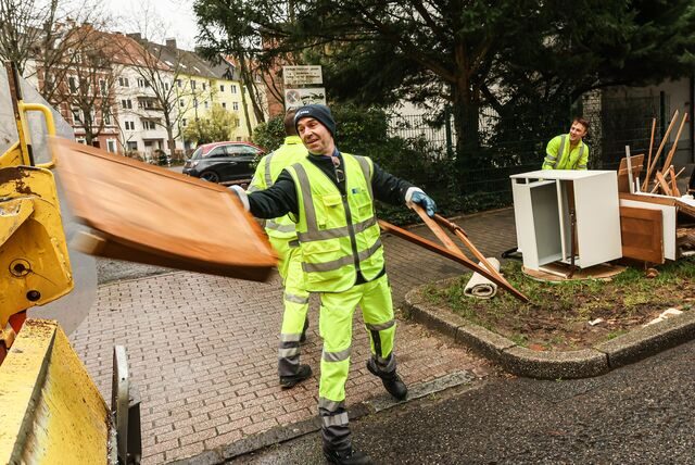 Ein Müllwerker wirft Sperrmüll in ein Müllfahrzeug