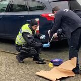 Ein Polizist und ein Kriminaltechniker sichern in einer Einfahrt an der Straße über den Knöchel in Herten einen Kinderrucksack und eine Mütze als Beweismittel.