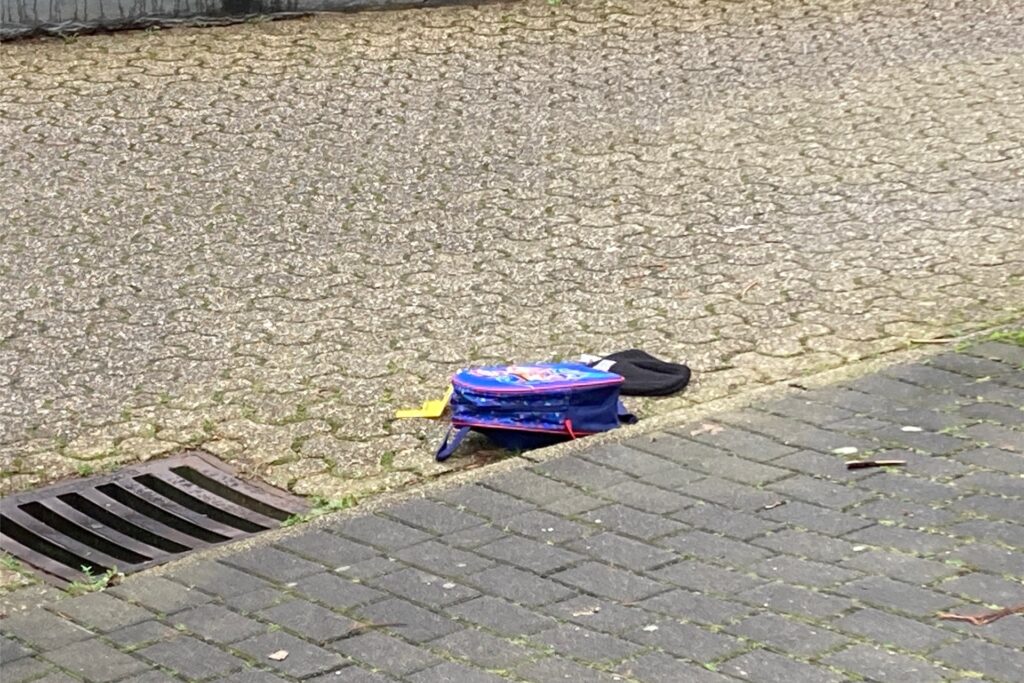 Ein Kinderrucksack und eine Mütze liegen auf der Fahrbahn.