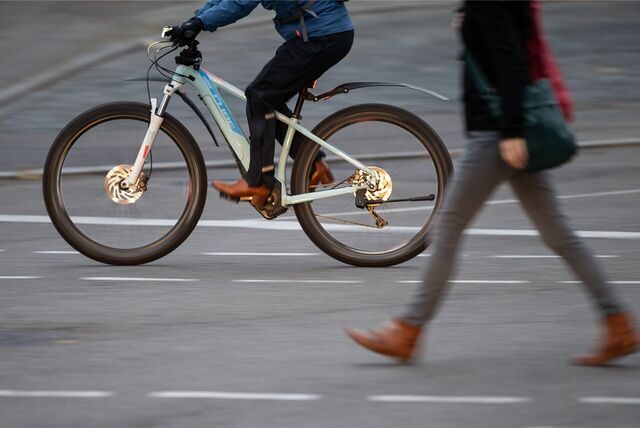 Ein E-Bike-Fahrer überholt eine Fußgängerin.