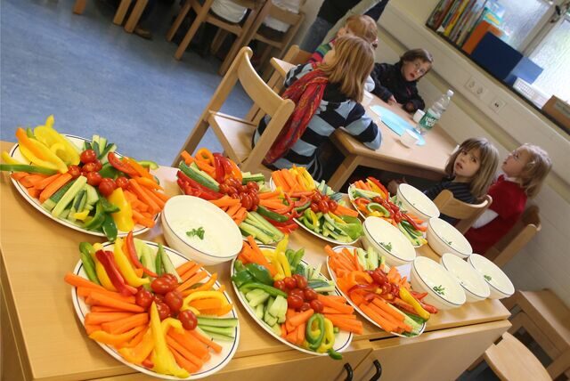 Kinder sitzen in einer OGS an neben einem Rohkost-Buffet. Das Symbolbild ist beispielhaft für die Betreuung in Oer-Erkenschwick.