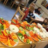 Kinder sitzen in einer OGS an neben einem Rohkost-Buffet. Das Symbolbild ist beispielhaft für die Betreuung in Oer-Erkenschwick.