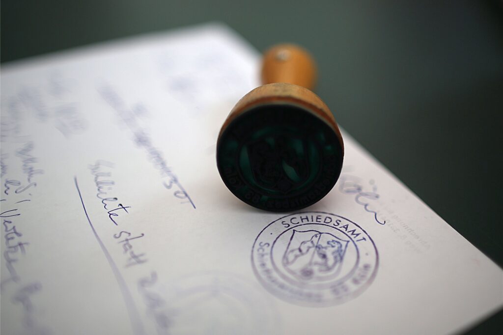 Der Stempel des Schiedsamtes liegt auf einem Papier. Der Stempel des Schiedsamtes liegt auf einem Papier.