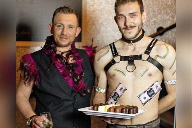 LGBTQ-Partyveranstalter Rene aus Dorsten mit einem Candyboy, der Schokoküsse auf einem Teller präsentiert.