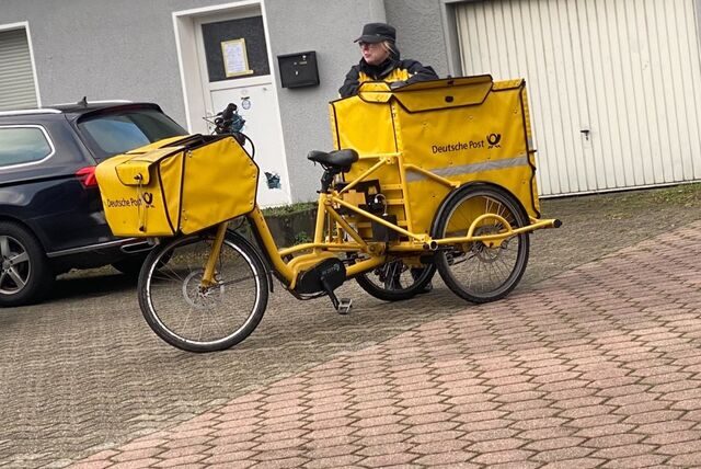 Eine Postbotin bringt mit dem Fahrrad in Dortmund die Post herum.