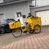 Eine Postbotin bringt mit dem Fahrrad in Dortmund die Post herum.
