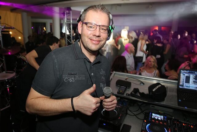 Marc Pesch, Co-Veranstalter des Waltroper Pyjamaballs, an einem DJ-Pult, im Hintergrund feiernde Menschen.