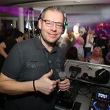 Marc Pesch, Co-Veranstalter des Waltroper Pyjamaballs, an einem DJ-Pult, im Hintergrund feiernde Menschen.