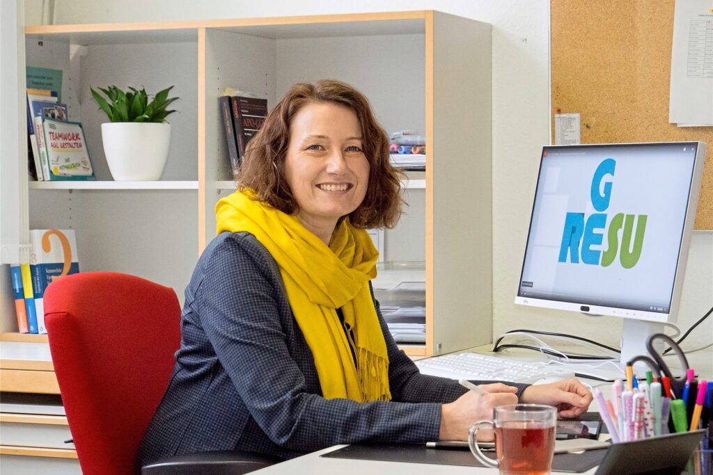 Schulleiterin Claudia Slowick sitzt an einem Computer und lächelt in die Kamera. Schulleiterin Claudia Slowick sitzt an einem Computer und lächelt in die Kamera.