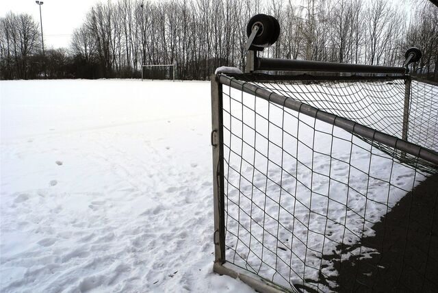 Der schneebedeckte Ascheplatz im Sportzentrum Nord in Waltrop; im Vordergrund ein auf die Seite gekipptes Tor.