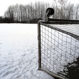 Der schneebedeckte Ascheplatz im Sportzentrum Nord in Waltrop; im Vordergrund ein auf die Seite gekipptes Tor.