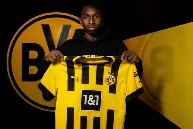 Moses Otuali hält ein BVB-Trikot in den Händen.