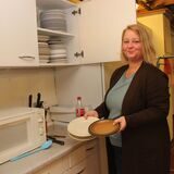 Lehrerin Farina Berger vor einem geöffneten Schrank der alten Schulküche am THG Waltrop mit einem Stapel Teller in der Hand.