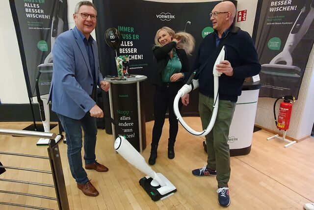 Bürgermeister Carsten Wewers steht an einem Vorwerk-Stand und probiert einen Staubsauger aus, daneben stehen eine Frau und ein Mann