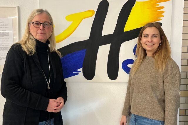 Schulleiterin Dagmar Perret und Lena Tesch stehen vor dem Logo der Joseph-Hennewig-Schule in Haltern.