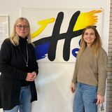 Schulleiterin Dagmar Perret und Lena Tesch stehen vor dem Logo der Joseph-Hennewig-Schule in Haltern.