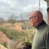 Josef Schürmann steht auf seinem Balkon und guckt in die Ferne.