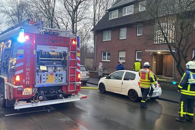Feuerwehrfahrzeug und Feuerwehrleute stehen vor einem Mehrfamilienhaus am Ostring in Waltrop.