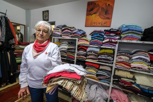 Ingrid Kallien trägt einen Stapel T-Shirts und steht vor Regalen voller Damen-Oberteile in der Kleiderkammer in Recklinghausen-Suderwich.