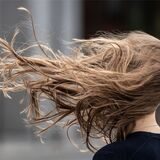 Die Haare einer Frau fliegen im Sturm.