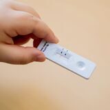 Ein Kind hält einen negativen Corona-Schnelltest in der Hand.