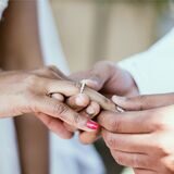 Ein Mann steckt seiner Frau einen Ring an den Finger.