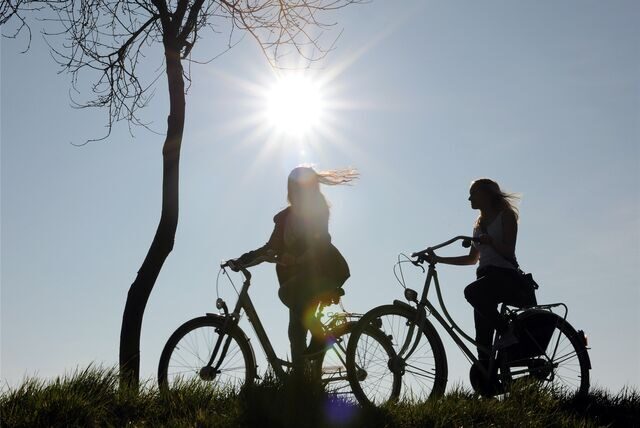 Zwei junge Radfahrerinnen sind im Gegenlicht bei frühlingshaftem Sonnenschein zu sehen (Symbolbild).