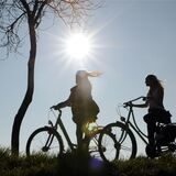 Zwei junge Radfahrerinnen sind im Gegenlicht bei frühlingshaftem Sonnenschein zu sehen (Symbolbild).