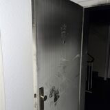 Wohnungstür mit Ruß bedeckt. Ein Handabdruck eines Feuerwehrmanns ist oberhalb des Spions zu erkennen.