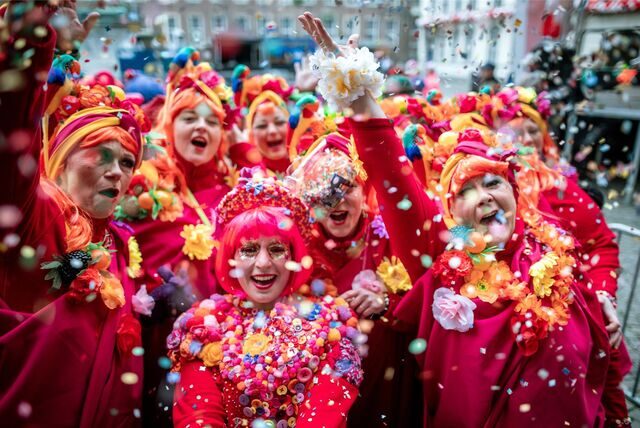 Verkleidete Frauen werfen an Karneval Konfetti in die Luft.