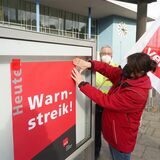 Ein Mitglied der Gewerkschaft Verdi befestigt ein Plakat an einem Schaukasten.