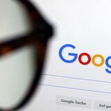 Die Seite der Suchmaschine von Google ist hinter einer Frau mit Brille zu sehen.