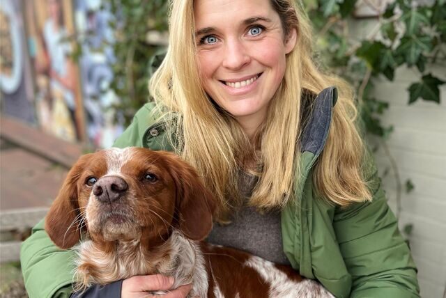 Eine Frau aus Recklinghausen hat einen mittelgroßen braun-weißen Hund auf dem Schoß.