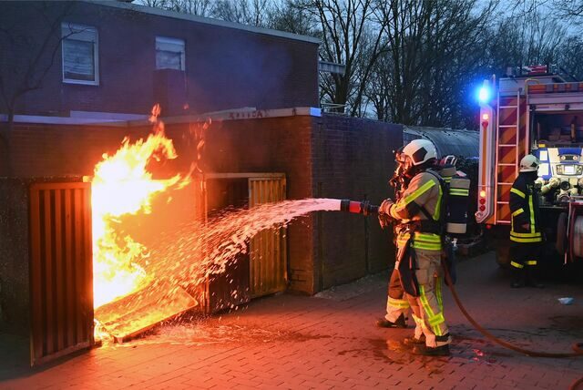 Die Feuerwehr löscht eine brennende Mülltonne.