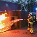 Die Feuerwehr löscht eine brennende Mülltonne.