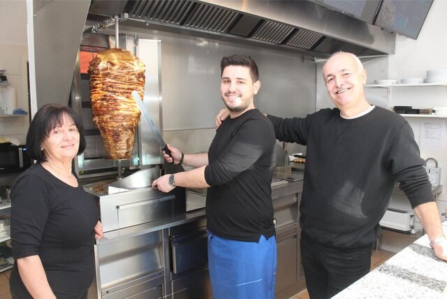 Achilleas Tzakos (M.), sein Vater Theofanis Tzakos und Mutter Eftischia Tsepi stehen am Gyros-Spieß im „Achillion-Grill“ an der Hochstraße in Waltrop.