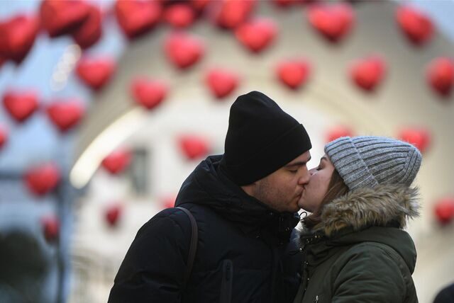 Ein Paar küsst sich, im Hintergrund sind Herz-Luftballons zu erkennen.