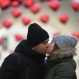 Ein Paar küsst sich, im Hintergrund sind Herz-Luftballons zu erkennen.