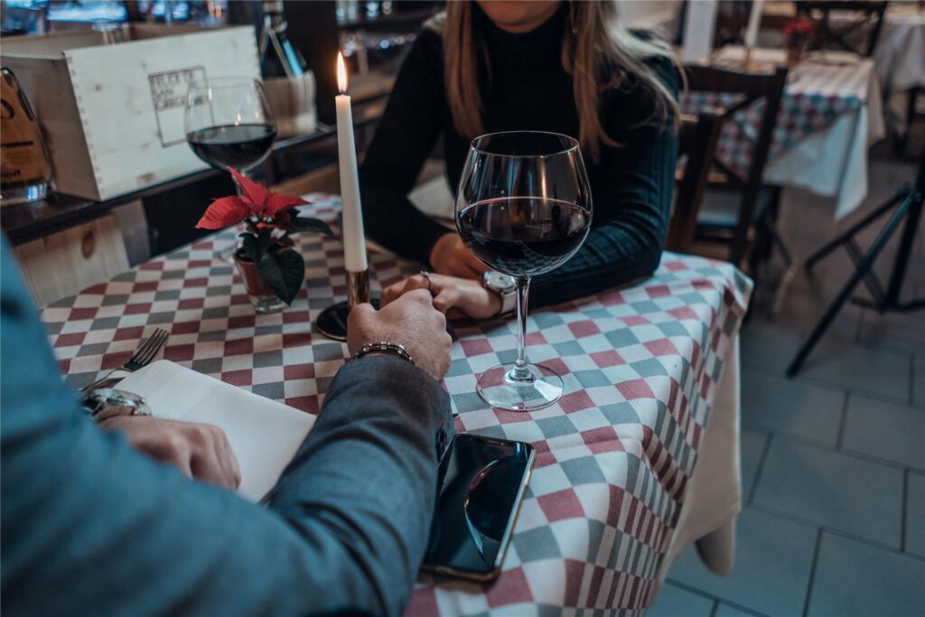 Ein Paar hält sich über den Tisch eines Restaurants hinweg an den Händen.