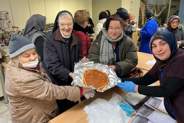 Jagoda Ristic, Schwester Aloysiana und Roswitha Vos kaufen gegen eine Spende Lahmacun, Nejla Kocaman bedient sie.