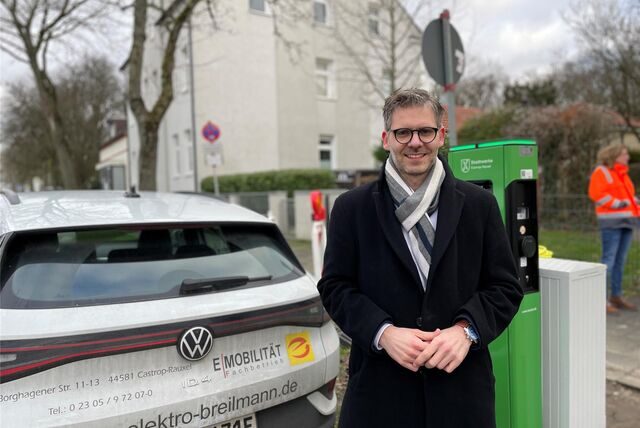 Jens Langensiepen, Chef der Stadtwerke in Castrop-Rauxel. Hinter ihm stehen ein E-Auto und eine Ladesäule.