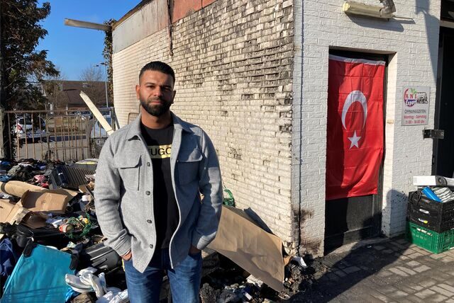 Vijay Raj, Geschäftsführer des Ani-Marktes in Lenkerbeck, steht vor den Resten der verbrannten Hilfsgüter. Im Hintergrund hängt wieder eine türkische Flagge.