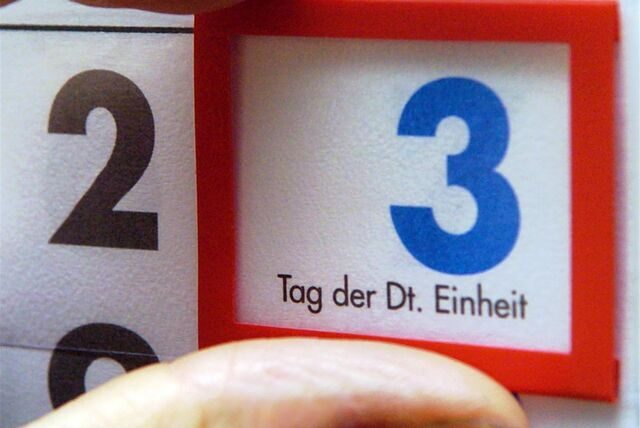 Eine Hand schiebt eine Markierung auf einem Kalender auf den 3. Oktober, den Tag der Deutschen Einheit.