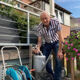 Ein Mann mit der Gießkanne vor einem Brunnen.