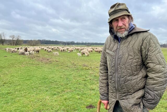 Erwin Biedermann steht auf einer Wiese in Rhade. Hinter ihm ist seine Schafherde.