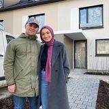 Ein junges Ehepaar steht vor dem Rohbau eines Reigenhauses.
